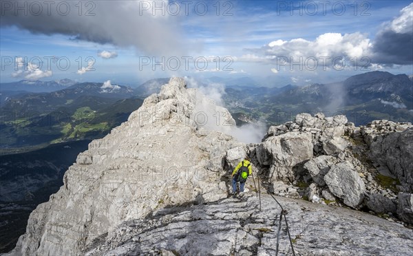 Climber on a via ferrata secured with steel rope, narrow rocky ridge, Watzmann crossing to Watzmann Mittelspitze, view of mountain panorama, Berchtesgaden National Park, Berchtesgaden Alps, Bavaria, Germany, Europe