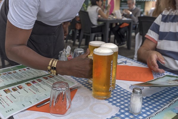 Waiter serves three beers at a table, Genoa, Italy, Europe