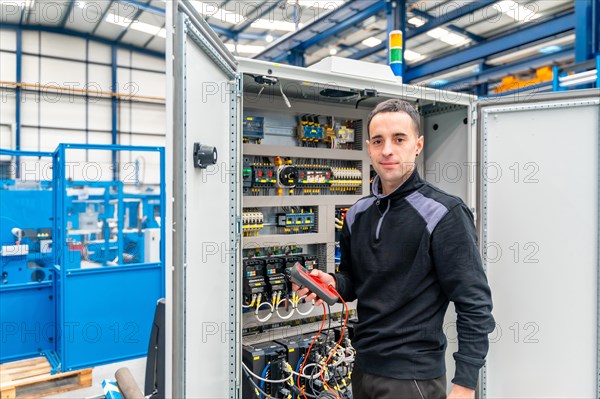 Portrait of a smiling male technician repairing an electrical mechanical system in a factory