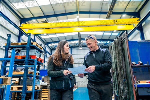 Teamwork of engineers talking and looking at a paper while working in a cnc logistics factory