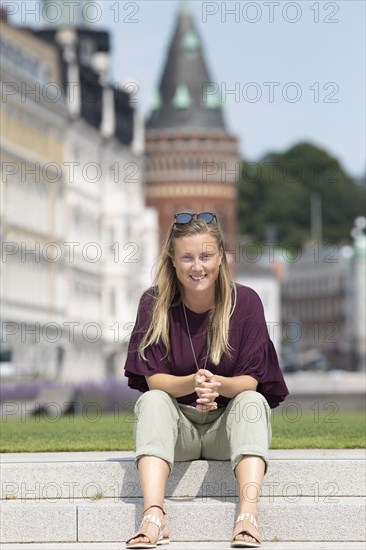 Swedish woman sitting on the steps in Angfaerjepark at the Kajpromenaden, portrait, behind the town hall, Helsingborg, province Skane laen, Sweden, Europe
