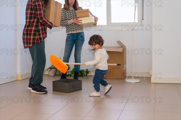 Cropped photo of a little girl playing with a broom while adults move house