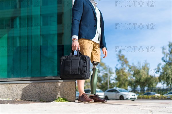 Lower part of an unrecognizable businessman with amputee leg standing in the financial district