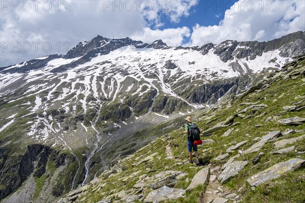 Mountaineer on rocky hiking trail, Berliner Hoehenweg, mountain landscape with snow-covered peak Gefrorene-Wand-Spitze, Zillertal Alps, Tyrol, Austria, Europe