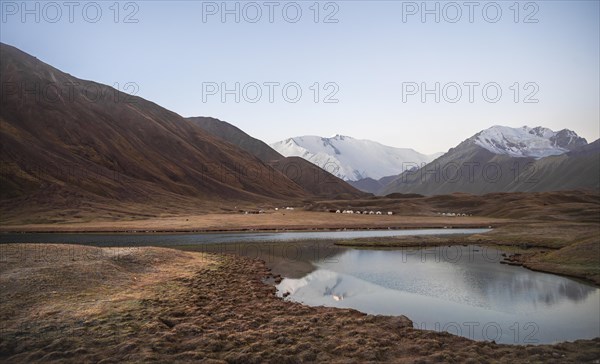 Yurts, mountains reflected in a small mountain lake, Pik Lenin, Trans Alay Mountains, Pamir Mountains, Osh Province, Kyrgyzstan, Asia