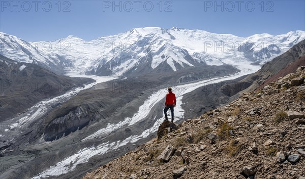 Mountaineer at Traveller's Pass with view of impressive mountain landscape, high mountain landscape with glacier moraines and glacier tongues, glaciated and snow-covered mountain peaks, Lenin Peak and Peak of the XIX Party Congress of the CPSU, Trans Alay Mountains, Pamir Mountains, Osh Province, Kyrgyzstan, Asia