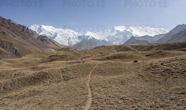 Hiking trail in the Achik Tash valley, behind glaciated and snow-covered mountain peak Lenin Peak and Peak of the XIX Party Congress of the CPSU, Trans Alay Mountains, Pamir Mountains, Osh Province, Kyrgyzstan, Asia