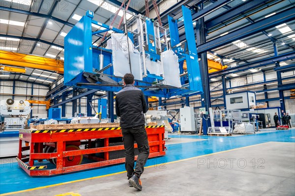 Worker using a crane to lift very heavy machinery in a factory