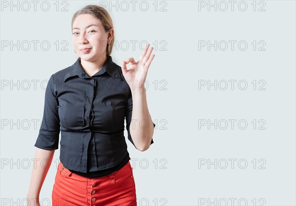 Positive beautiful girl showing ok gesture isolated. Portrait of cheerful young woman gesturing ok approved