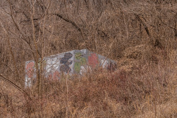 Small concrete building painted in camouflage colors in dense mountainside bush