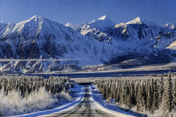 Highway in winter landscape in front of snow-covered mountains, Alaska Highway, Haines Junction, Yukon Territory, Canada, North America