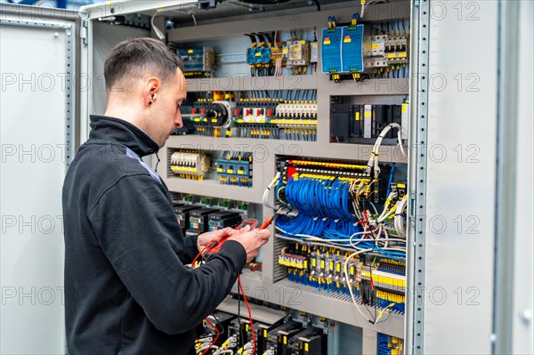 Rear view of a male worker repairing an electrical mechanical system in a factory