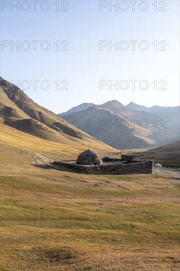 Historic caravanserai Tash Rabat from the 15th century, in the evening light with golden hills, Naryn region, Kyrgyzstan, Asia