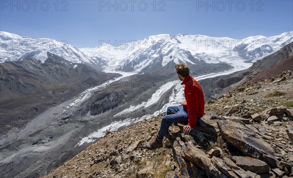 Mountaineer at Traveller's Pass with view of impressive mountain landscape, high mountain landscape with glacier moraines and glacier tongues, glaciated and snow-covered mountain peaks, Lenin Peak and Peak of the XIX Party Congress of the CPSU, Trans Alay Mountains, Pamir Mountains, Osh Province, Kyrgyzstan, Asia