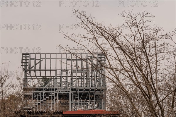 Metal frame of unfinished building abandoned in wooded countryside on an overcast day