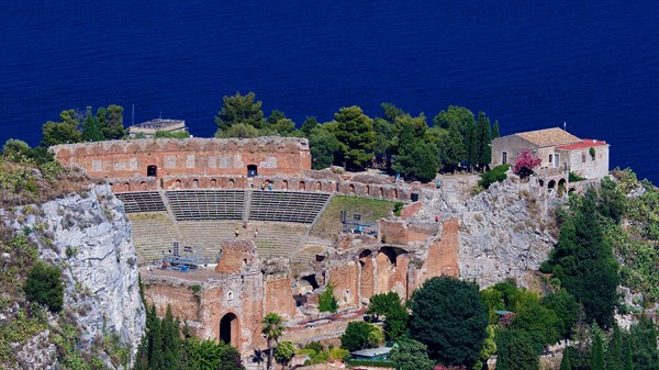Remains of an ancient theatre on a cliff overlooking the sea under a clear blue sky, Taormina, Eastern Sicily, Sicily, Italy, Europe