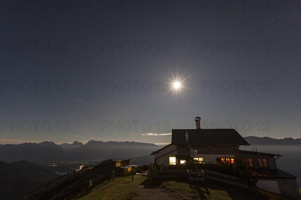Mountain hut at full moon in front of mountains, at night, illuminated, Wankhaus, view of Karwendel mountains, Bavaria, Germany, Europe