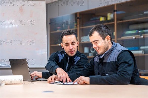 Two engineers talking sitting in a meeting room of a factory
