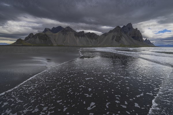 Vestrahorn, mountains with black lava sand, reflection in the water, south coast of Iceland