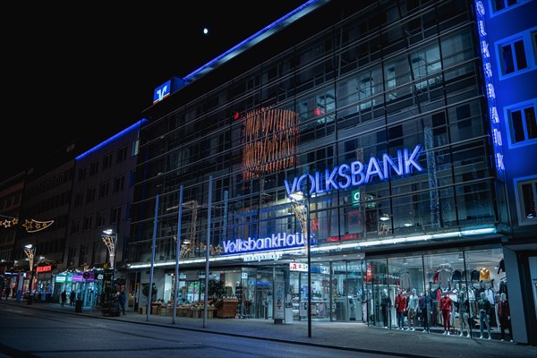 Modern bank branch with illuminated glass facade in a nocturnal urban scene, Volksbankhaus, Pforzheim, Germany, Europe