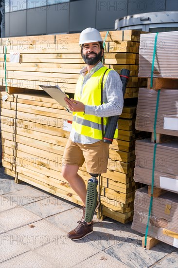 Vertical portrait of a smiley engineer with amputee leg working in a construction site