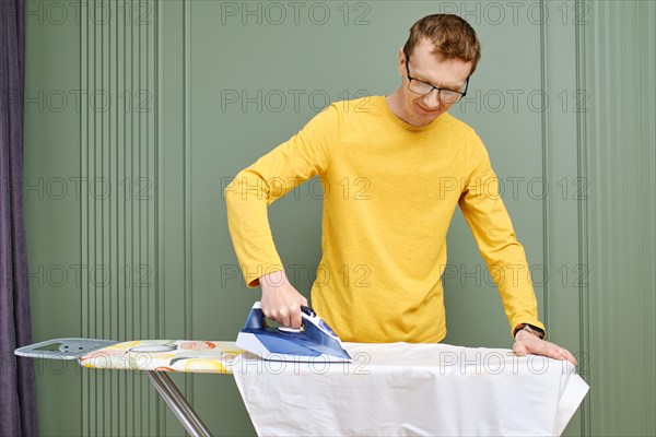 Separation of household duties concept. Mid aged man ironing his shirt