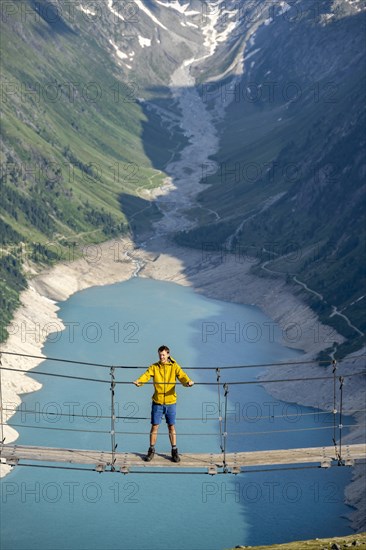 Mountaineers on a suspension bridge, picturesque mountain landscape near the Olpererhuette, view of turquoise-blue lake Schlegeisspeicher, Berliner Hoehenweg, Zillertal Alps, Tyrol, Austria, Europe