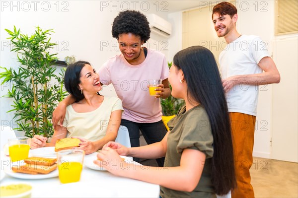 Friends embracing while having fun in the morning at home during breakfast