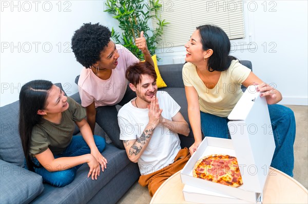 Top view of a group of multi-ethnic hungry friends opening a delivered pizza box