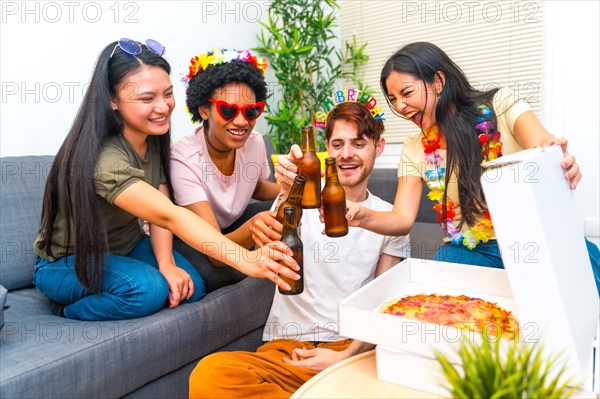 Multi-ethnic happy friends toasting with beer during a birthday party at home