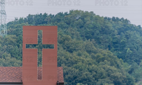 Large Christian cross attached to roof of house in countryside