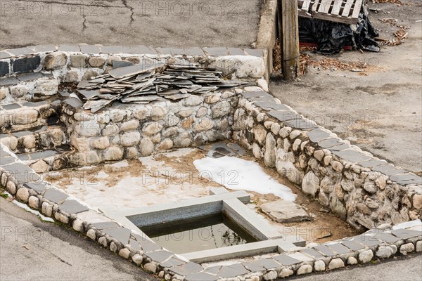 Remains of building foundation made of stone and concrete with square pool of water in center