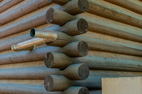 Metal exhaust pipe protruding from side exterior wall of wood log building