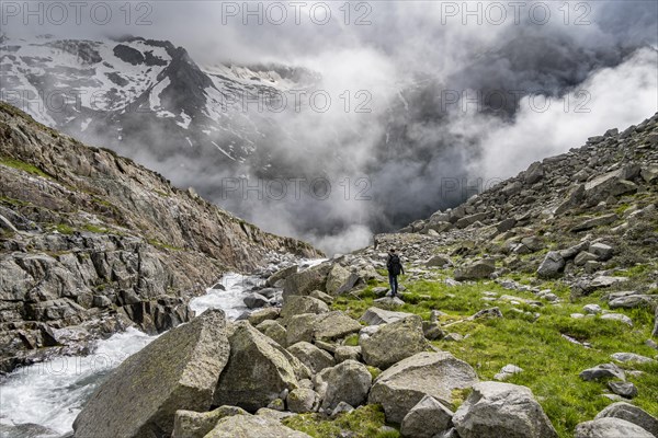 Mountaineer at a mountain stream, Furtschaglbach, cloudy mountains in the background, Furtschaglhaus, Berliner Hoehenweg, Zillertal, Tyrol, Austria, Europe