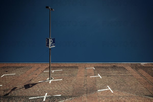 Street lamp and car park sign against a clear blue sky on a brick wall, Cologne Deutz, North Rhine-Westphalia, Germany, Europe