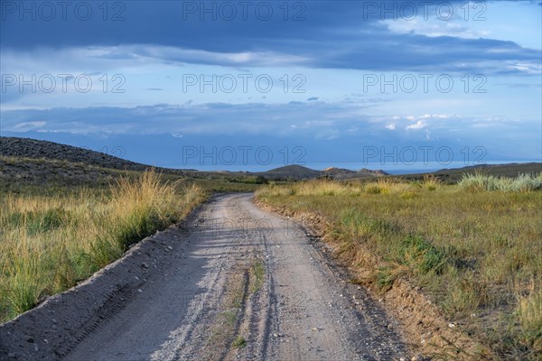 A gravel track leads through a barren field landscape, Kyrgyzstan, Asia