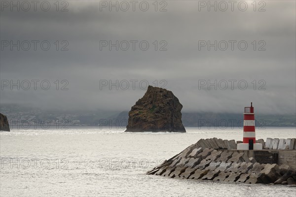 Breakwater and lighthouse by the sea with a rocky island 'Iieu em Pe' in the background on a foggy day, Iieu Deitado, Iieu em Pe, Horta, Faial, Azores, Portugal, Europe