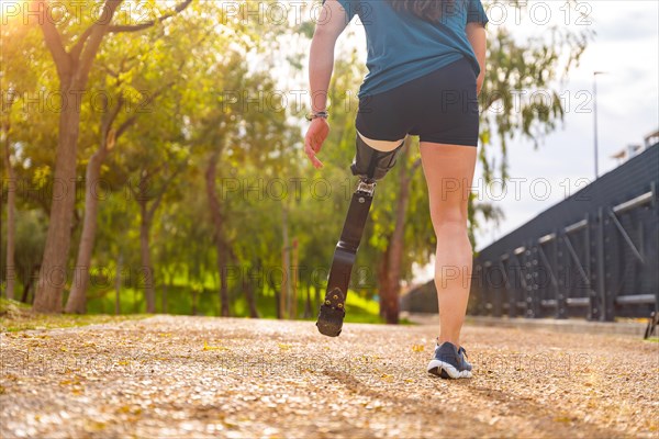 Close-up rear view of a disabled man with prosthetic leg running outdoors