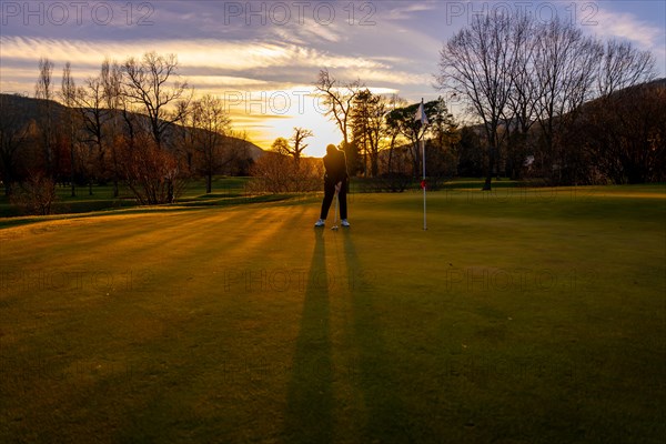 Female Golfer Concentration on the Putting Green on Golf Course in Sunset in Switzerland