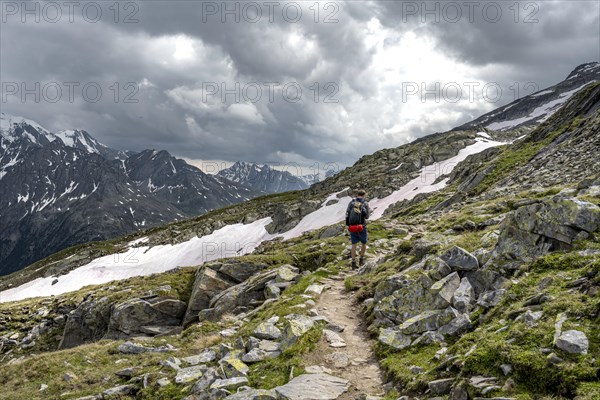 Mountaineer on hiking trail with snow, Berliner Hoehenweg, mountain landscape with rocky peaks, Zillertal Alps, Tyrol, Austria, Europe