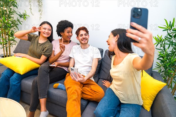 Multi-ethnic friends having fun taking a selfie sitting together in a couch at home