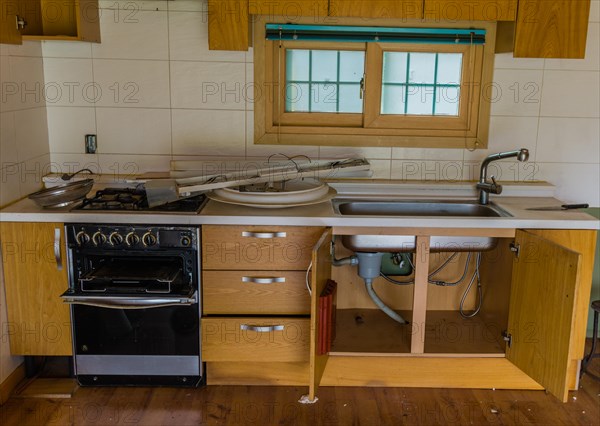 Kitchen cabinets of abandoned house with electrical fixtures debris on counter top