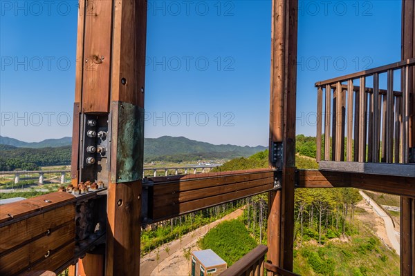 Wooden beams of tower on mountain top at public park with view of landscape and structures below in background