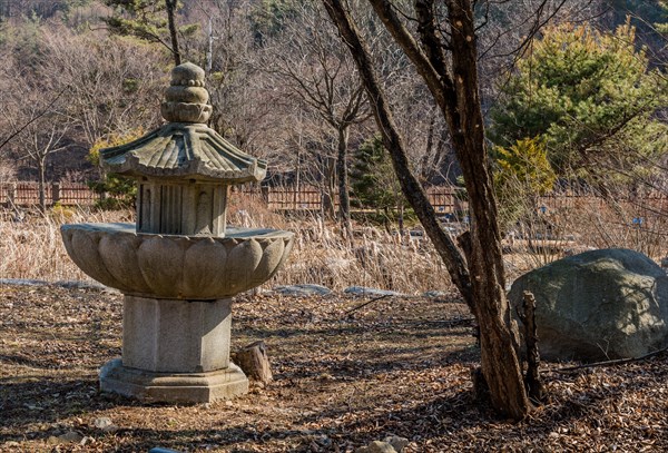 Stone carved pagoda in run down garden on sunny afternoon