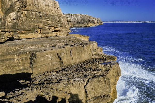 Beautiful cliffs and rock formations in Peniche, Portugal, on sunny day. Weathered rock formations, geological interest, cliffs, blue sea waves, tide, coastline, clear blue sky, Europe