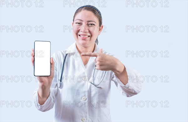 Young female doctor showing and pointing at smatphone screen isolated. Smiling female doctor holding and pointing at phone screen