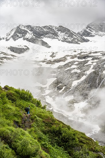 Mountaineers on a hiking trail, in the background glaciated peak Dosso Largo and glacier Schlegeiskees, cloudy atmospheric mountain landscape, ascent to Furtschaglhaus, Berliner Hoehenweg, Zillertal, Tyrol, Austria, Europe