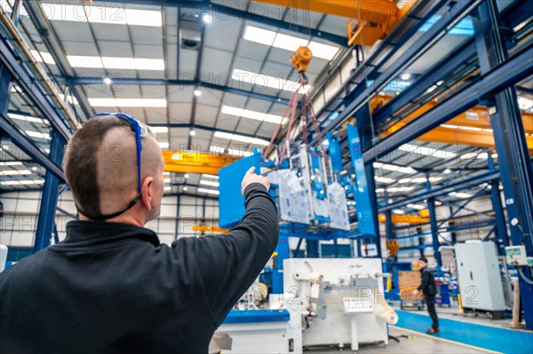 Rear view of a worker directing the maneuvers of an industrial crane