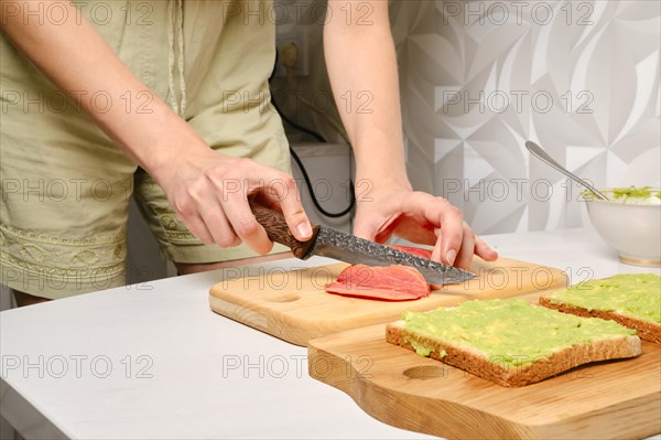 Unrecognizable woman slicing smoked salmon with knife