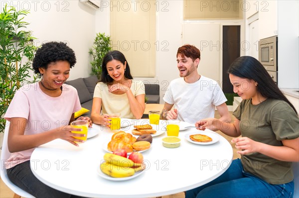 Happy friends having a healthy breakfast together sitting in a table at the apartment